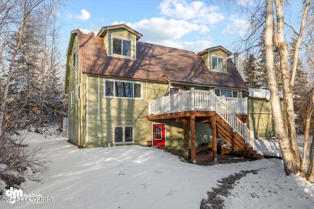 snow covered back of property featuring a deck