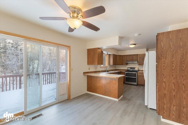 kitchen featuring kitchen peninsula, ceiling fan, electric range, light hardwood / wood-style flooring, and white fridge