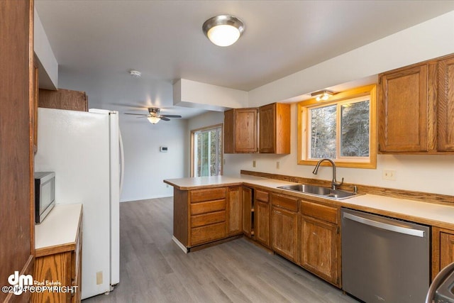 kitchen featuring ceiling fan, sink, stainless steel appliances, kitchen peninsula, and light hardwood / wood-style floors