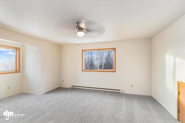 carpeted empty room featuring a wealth of natural light, a baseboard heating unit, and ceiling fan