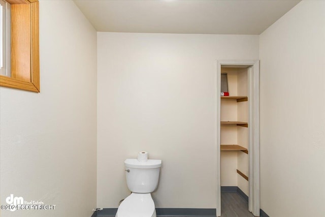 bathroom featuring built in features, wood-type flooring, and toilet