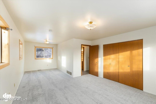 unfurnished bedroom with light carpet and a closet