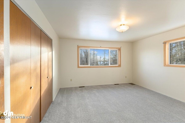 unfurnished bedroom with light carpet and a closet