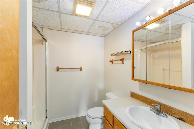 bathroom featuring a drop ceiling, tile patterned floors, an enclosed shower, toilet, and vanity