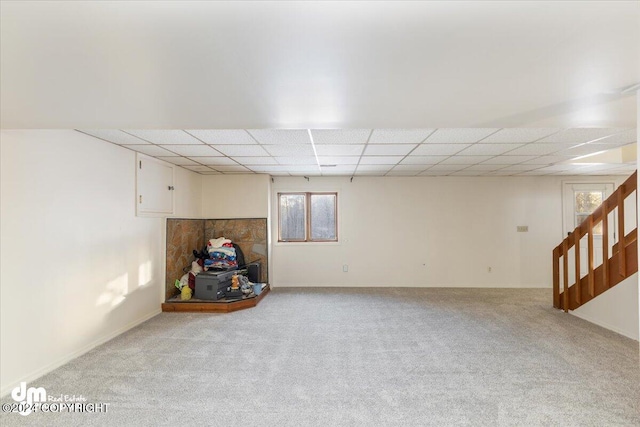 basement featuring a drop ceiling and light colored carpet