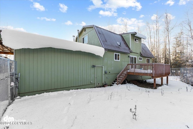 snow covered rear of property with a wooden deck