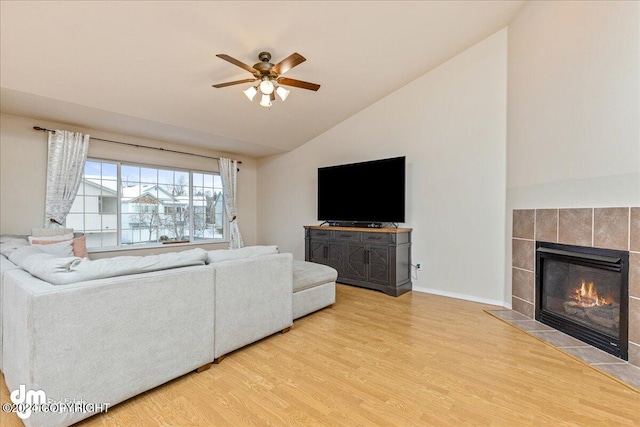 living room with hardwood / wood-style flooring, ceiling fan, a tile fireplace, and lofted ceiling