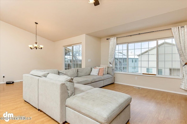 living room featuring hardwood / wood-style floors, a notable chandelier, a healthy amount of sunlight, and vaulted ceiling