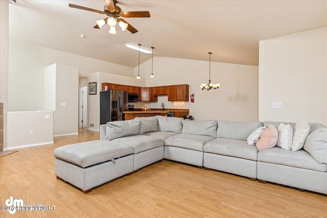 living room featuring light hardwood / wood-style floors, ceiling fan with notable chandelier, sink, and lofted ceiling