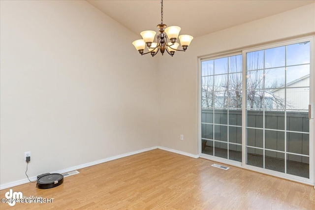 spare room with a chandelier, wood-type flooring, and lofted ceiling