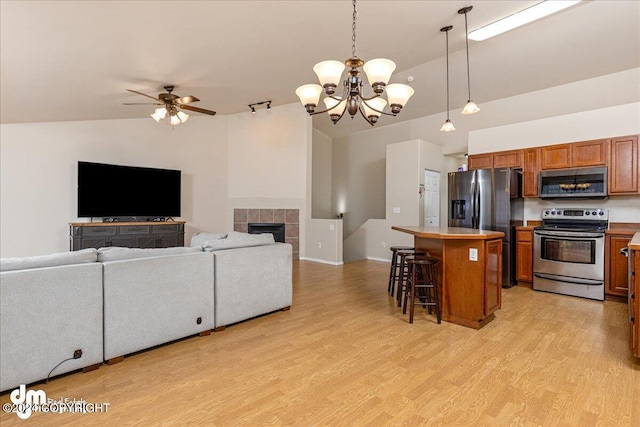 kitchen featuring stainless steel appliances, vaulted ceiling, hanging light fixtures, a kitchen island, and a fireplace