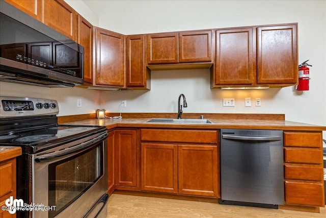 kitchen with light hardwood / wood-style floors, stainless steel appliances, and sink