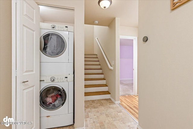 clothes washing area featuring stacked washing maching and dryer and light wood-type flooring