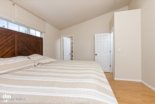 unfurnished bedroom featuring light wood-type flooring and lofted ceiling