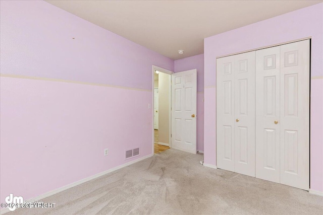 unfurnished bedroom with a closet and light carpet