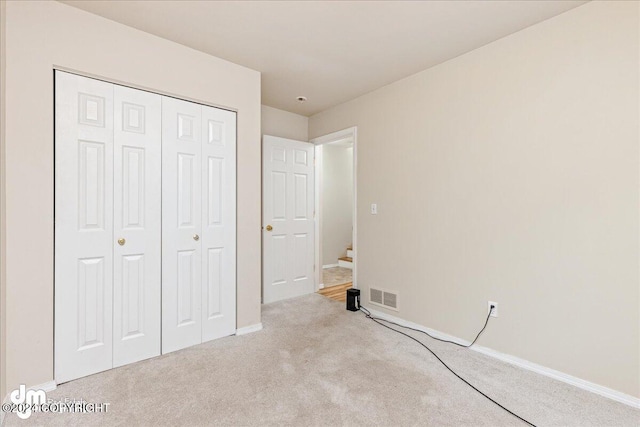 unfurnished bedroom with light carpet and a closet