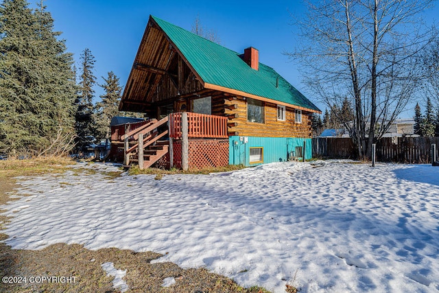 snow covered back of property featuring a wooden deck