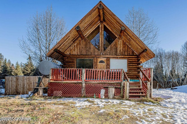 view of front of house featuring a deck, fence, and log exterior
