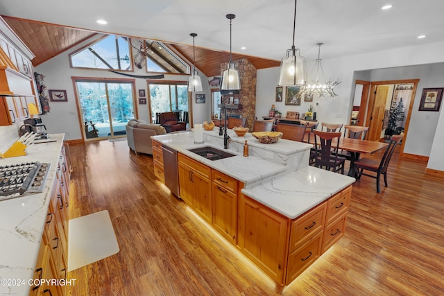 kitchen with light stone countertops, sink, stainless steel appliances, light hardwood / wood-style floors, and decorative light fixtures