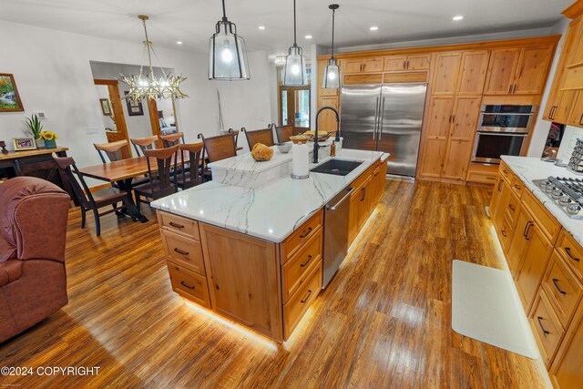 34184 House Dr, Soldotna, AK 99669 - kitchen featuring appliances with stainless steel finishes, wood finished floors, a sink, open floor plan, and light stone countertops