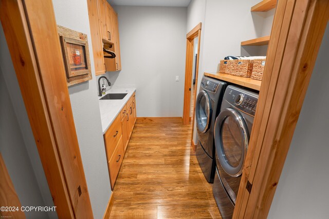 34184 House Dr, Soldotna, AK 99669 - laundry room featuring independent washer and dryer, light wood-type flooring, cabinet space, and baseboards
