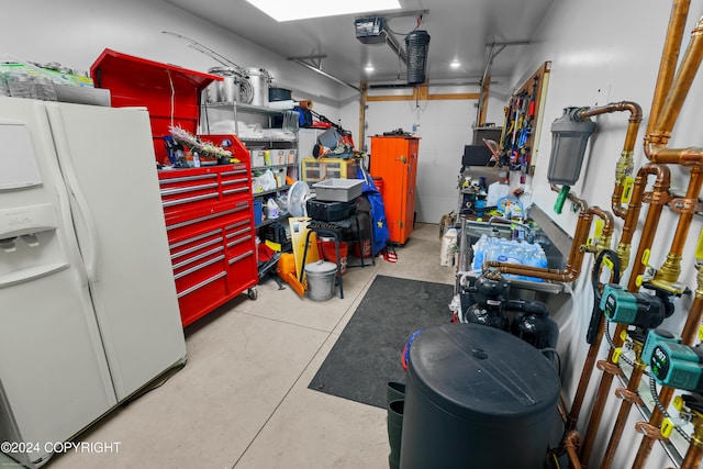 34184 House Dr, Soldotna, AK 99669 - garage with white refrigerator with ice dispenser, a garage door opener, and a workshop area