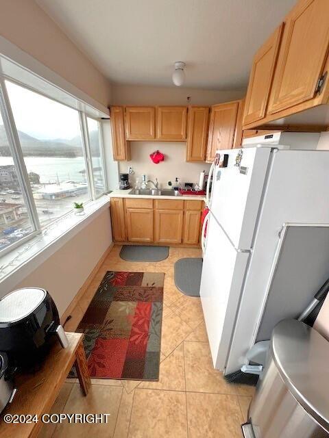 kitchen with white fridge, sink, and light brown cabinetry