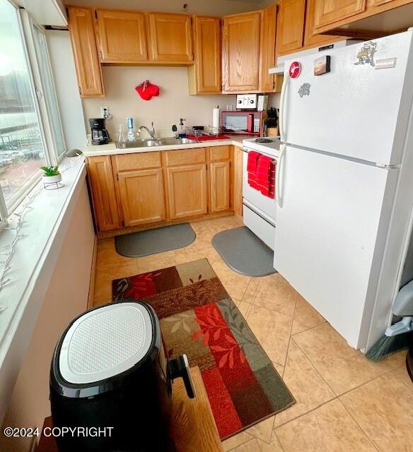 kitchen featuring white appliances, sink, and light tile patterned floors