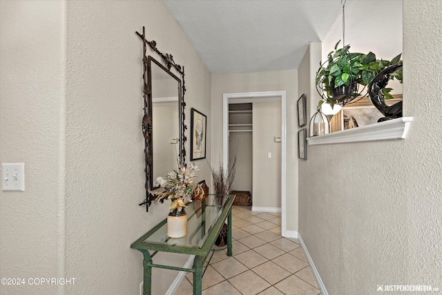 corridor with a barn door, light tile patterned floors, and a textured ceiling