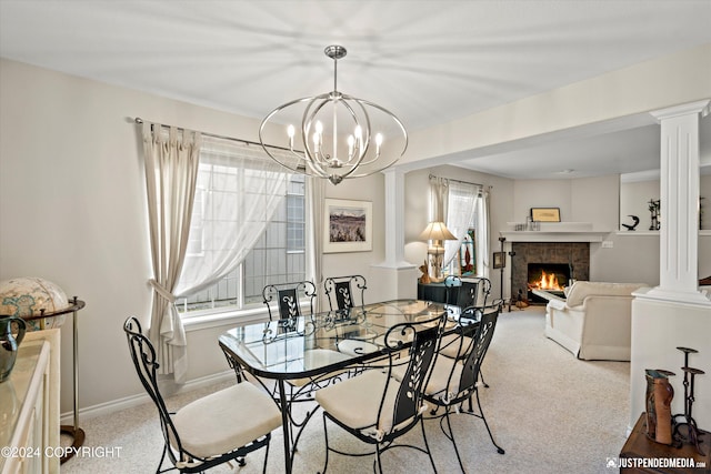 dining space with ornate columns, a fireplace, light colored carpet, and a notable chandelier