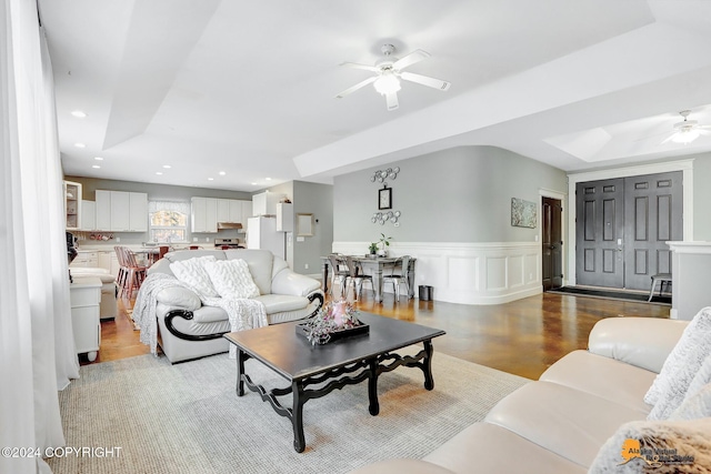 living room featuring a raised ceiling, ceiling fan, and light hardwood / wood-style flooring