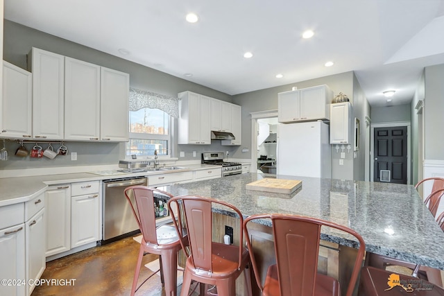 kitchen featuring light stone countertops, stainless steel appliances, a kitchen island, and white cabinets