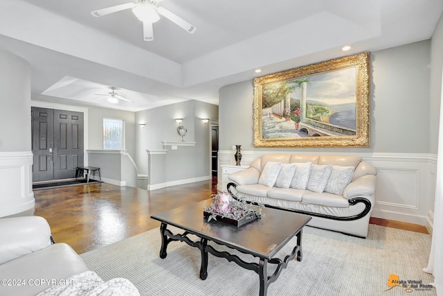 living room with a raised ceiling and ceiling fan