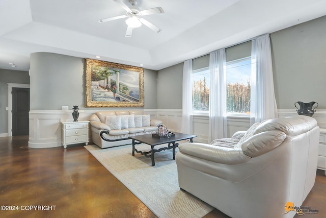 living room featuring ceiling fan and a raised ceiling