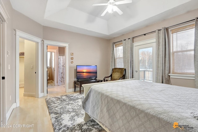 bedroom featuring a tray ceiling, access to exterior, ceiling fan, and light hardwood / wood-style floors