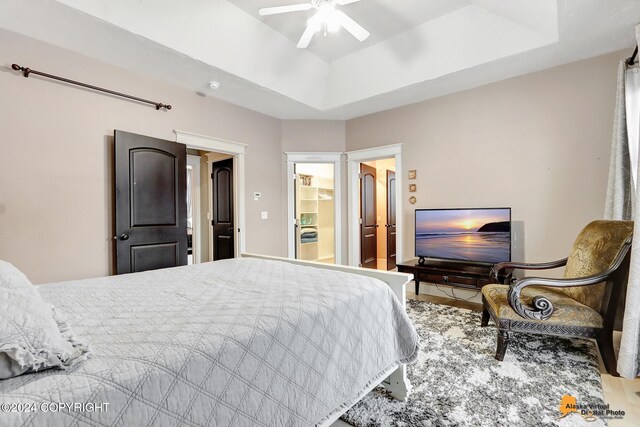 bedroom with a raised ceiling, ceiling fan, and hardwood / wood-style floors