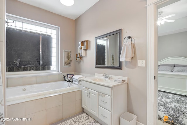 bathroom with vanity, tiled bath, ceiling fan, and a healthy amount of sunlight