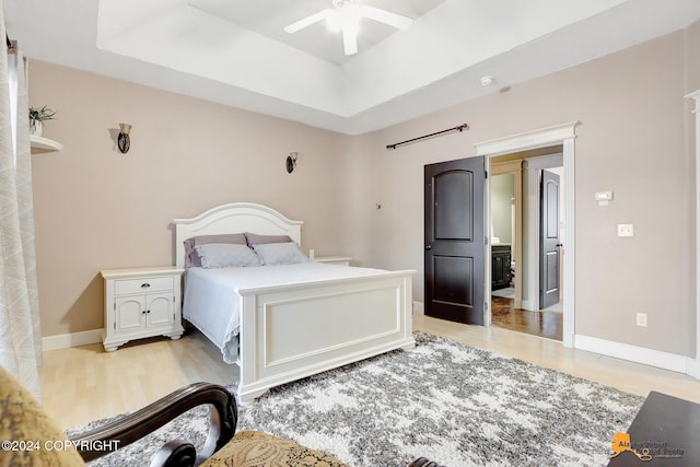 bedroom featuring light hardwood / wood-style floors, ceiling fan, and a tray ceiling