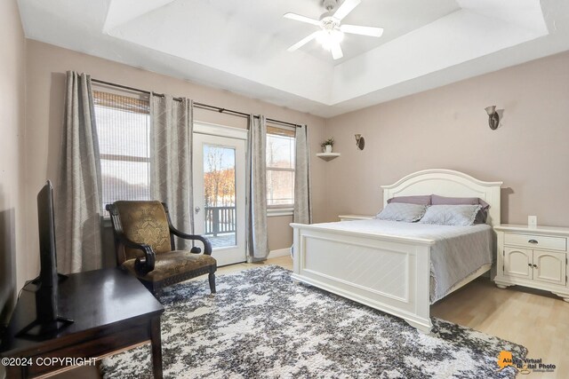 bedroom featuring access to exterior, a tray ceiling, ceiling fan, and light hardwood / wood-style floors