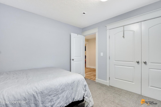 bedroom featuring a textured ceiling, light colored carpet, and a closet