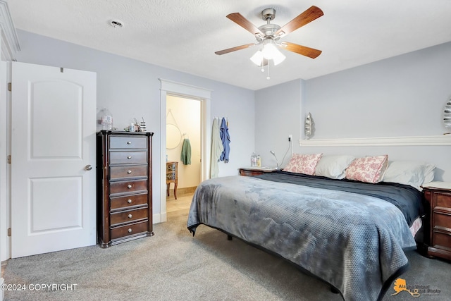 carpeted bedroom featuring ceiling fan and a textured ceiling