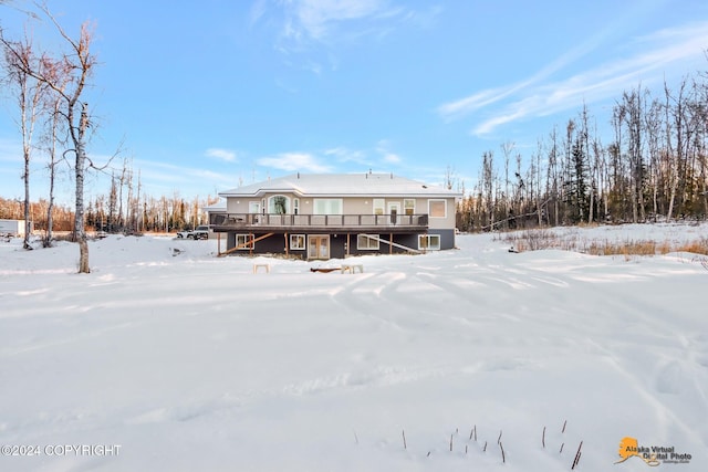 snow covered rear of property with a deck