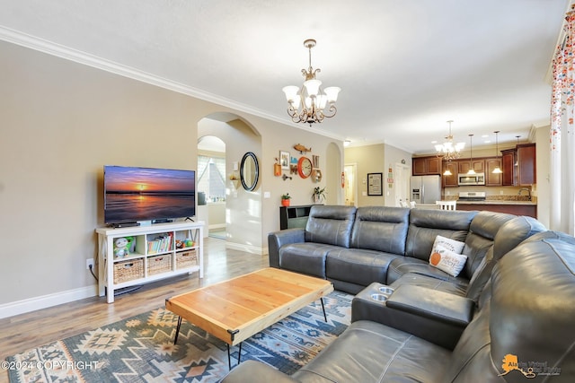 living room with sink, light hardwood / wood-style floors, ornamental molding, and a notable chandelier