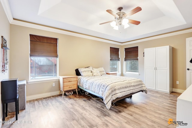 bedroom with a tray ceiling, ceiling fan, crown molding, and light wood-type flooring