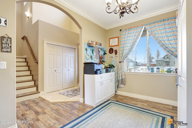 entryway featuring a chandelier, hardwood / wood-style flooring, and crown molding