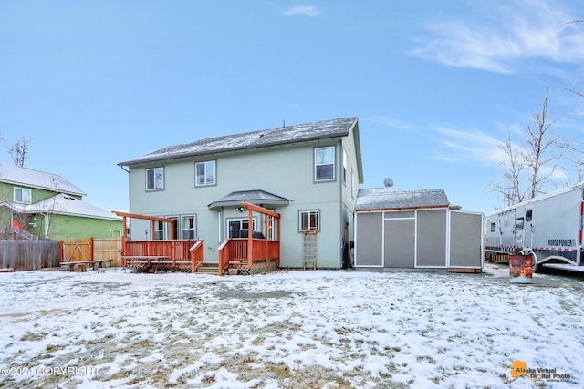 snow covered back of property with a wooden deck