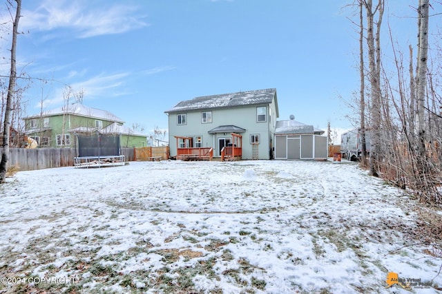 snow covered property with a trampoline and a deck