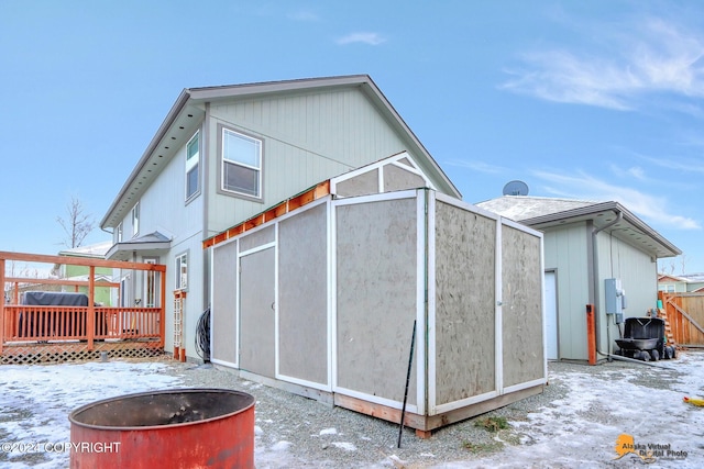 snow covered rear of property featuring a deck