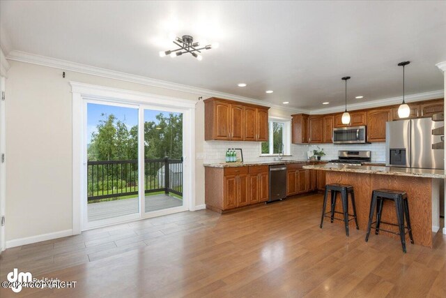 kitchen featuring decorative light fixtures, backsplash, light stone counters, stainless steel appliances, and crown molding