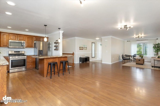 kitchen featuring pendant lighting, light hardwood / wood-style flooring, a breakfast bar, stainless steel appliances, and light stone counters